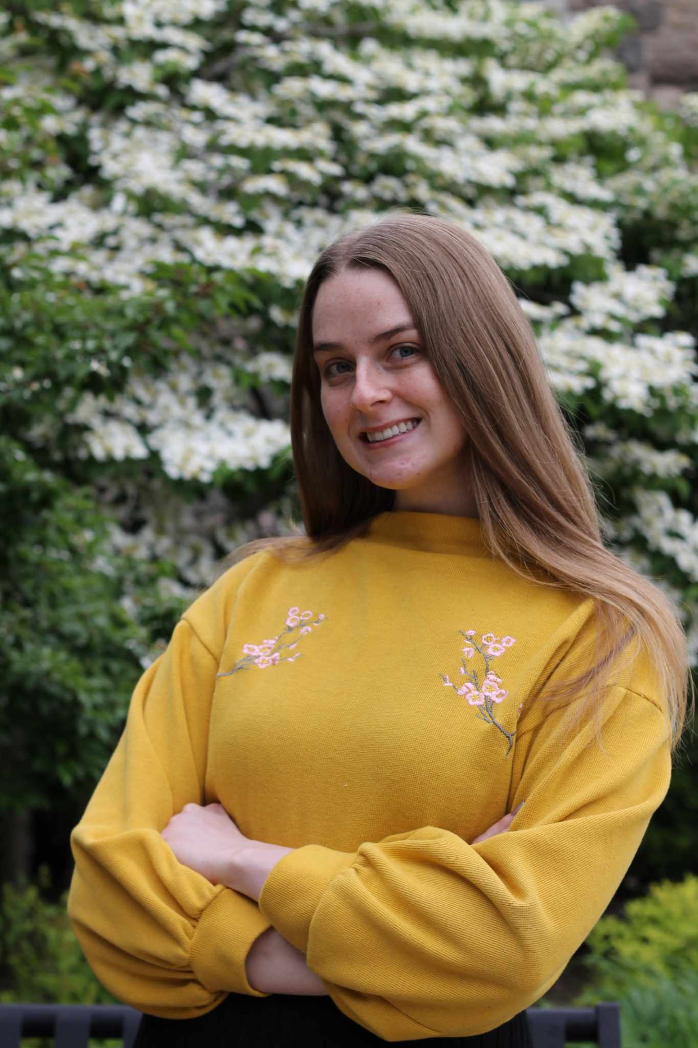 A woman wearing a yellow shirt smiles at the camera.