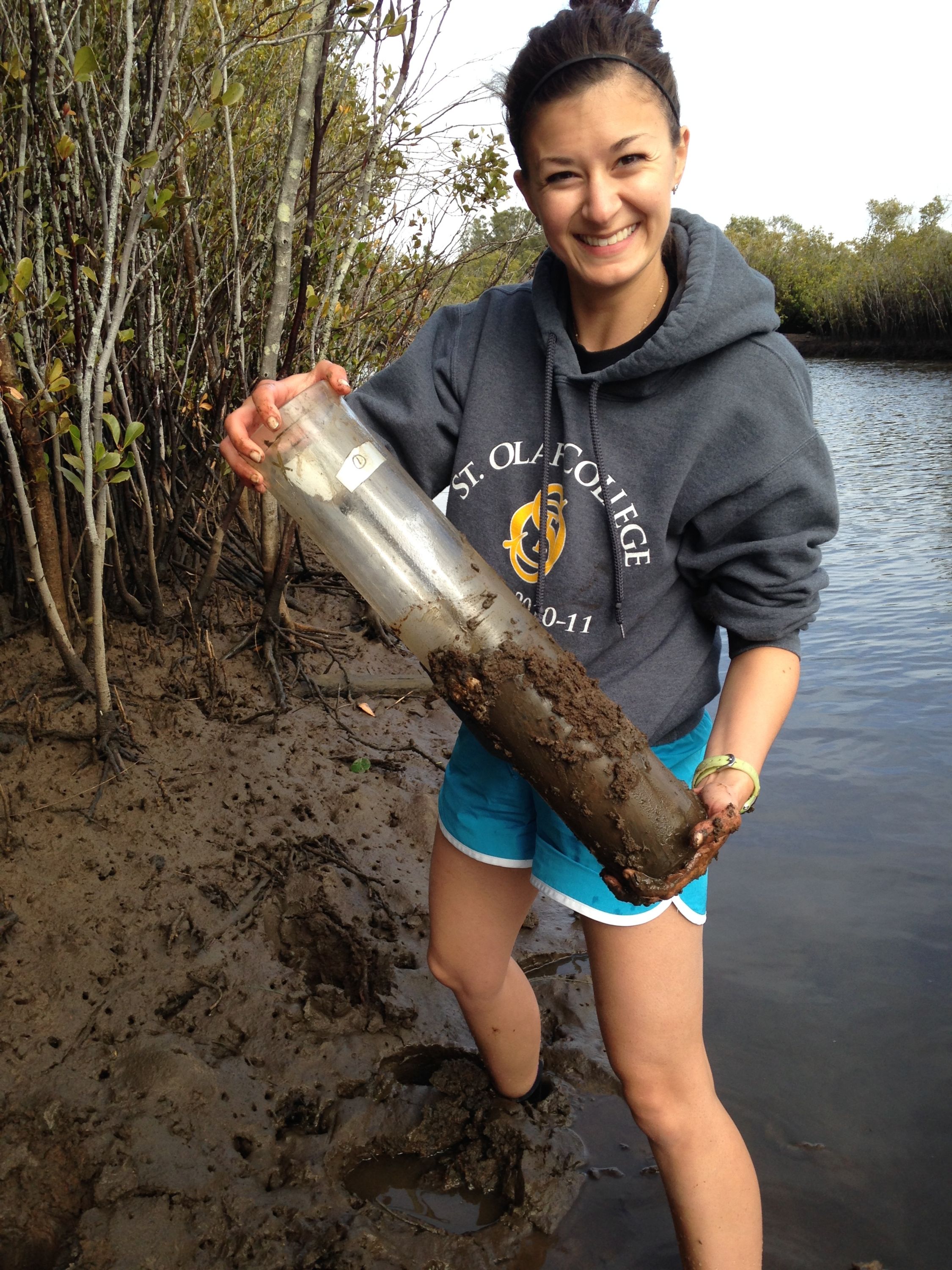 Kateri Salk standing in the mud holding a soil sample