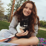 Kayleigh Goodrich sitting on a blanket outside holding her cat