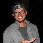 Matthew Welc standing in the dark holding an amphibian